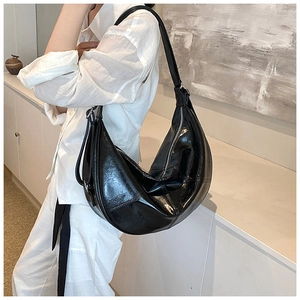 Detail of black crescent shoulder bag with glossy wrinkled texture and adjustable strap