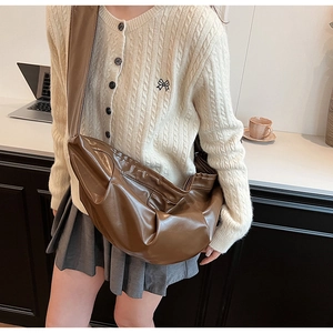 Detail of dark brown glossy pleated dumpling bag with soft leather texture for daily wear