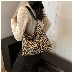 Detail view of large leopard print tote bag with black leather strap and gold logo