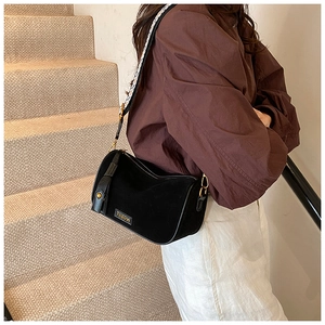 Detail of black cylindrical pillow bag with wide geometric strap and gold hardware