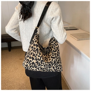 Chic leopard print hobo bag with adjustable black strap shown on model in modern room