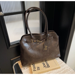 Detail of dark brown vintage PU leather tote showing textured finish and golden buckle