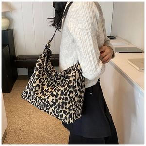 Close-up of leopard print tote bag with black leather strap and gold buckle detail