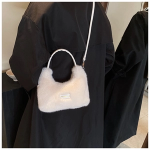 Detail of soft white faux fur handbag with 'love every day' patch on black coat background