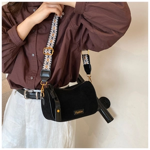 Detail of black suede crossbody bag with geometric woven strap and gold hardware