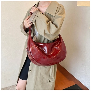 Deep red patent leather hobo bag worn by model, highlighting its glossy finish and large capacity