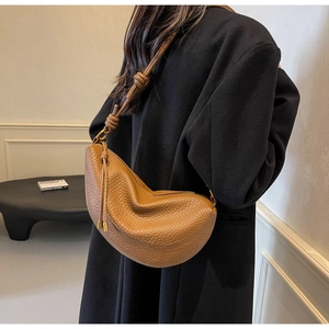 Close-up of brown pebbled leather crescent bag with knot detail and metal ring