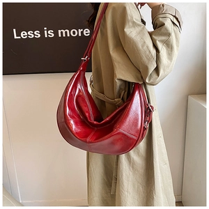 Detail view of a stylish red crescent bag with smooth leather texture and silver hardware