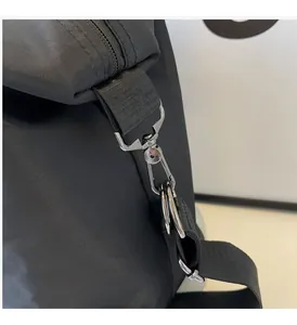 Detail of glossy silver metal spring hook and D-ring on black nylon travel bag strap
