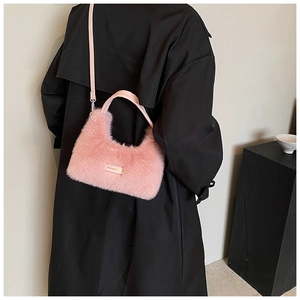 Detailed shot of plush pink faux fur crossbody bag with leather handles on black coat