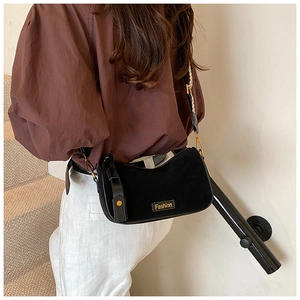 Fashionable black suede half-moon crossbody bag shown on a model in a modern setting