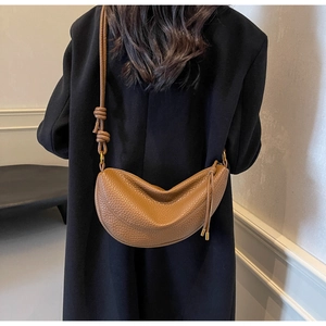Detail of caramel crescent crossbody bag with lychee grain leather and knotted strap