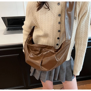 Detailed view of the brown semi-moon shoulder bag with glossy PU leather and wide strap