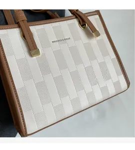 Detail of white brick texture fabric and brown leather trim on a fashion tote bag