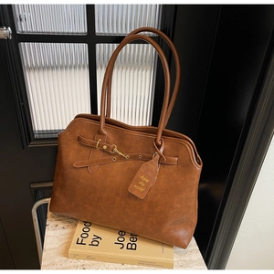Macro view of vintage brown leather tote bag showing fine grain texture and gold buckle detail