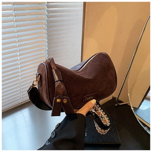 Close-up of brown suede pillow bag with golden hardware and ethnic geometric strap