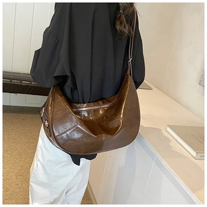 Macro view of brown hobo shoulder bag with vertical stitching and silver zipper detail