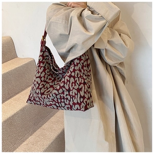 Detail shot of animal pattern woven tote bag with premium red leather shoulder straps