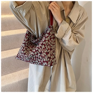 Detail of red jacquard bucket bag with leopard pattern and leather strap on model