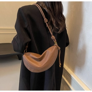 Close-up of brown pebbled leather shoulder bag with knotted strap on wool coat