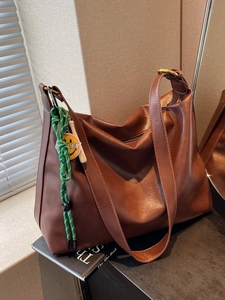 Sac hobo marron en cuir avec bandoulière tressée et pendentif smiley dans un salon