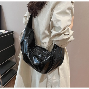 Detailed view of a black patent leather crescent shoulder bag with high-gloss finish