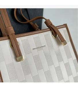 Detail of two-tone tote bag featuring geometric perforated texture and gold ring charm