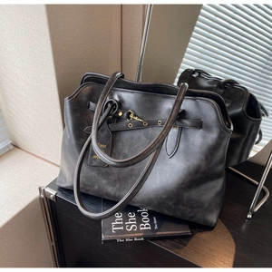 Close-up of vintage black leather tote bag featuring distressed texture and metal ring