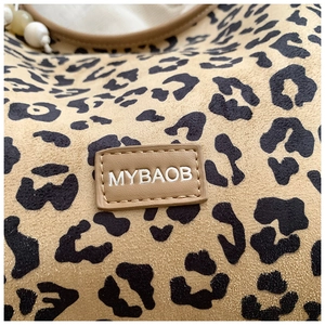 Close-up of leopard print suede texture and leather logo tag on a large shoulder bag