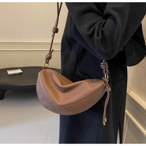 Close-up of caramel brown crescent bag showing premium lychee grain leather texture