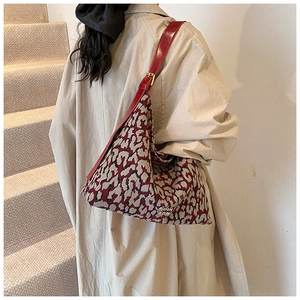 Detail of red jacquard tote bag with adjustable shoulder strap and gold buckle detail