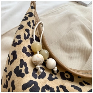 Detail of leopard print shoulder bag featuring suede texture and decorative beaded tassel