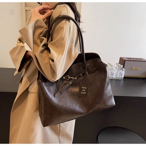 Detail of dark brown leather tote bag with decorative straps and gold metal buckles