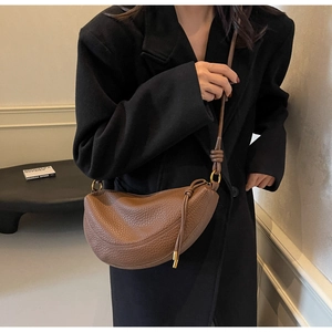Detail of vintage brown pebble leather crescent crossbody bag with gold-tone hardware