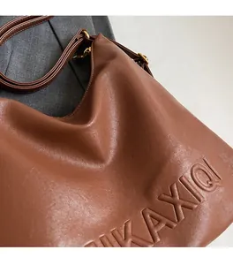 Dettaglio della borsa tote in ecopelle marrone con logo a rilievo e texture