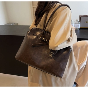 Detail of dark brown leather tote bag showing large capacity and vintage buckle design