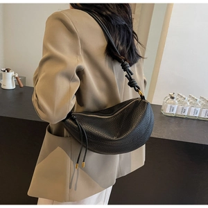Detail of black pebbled leather crescent bag featuring a unique knotted shoulder strap