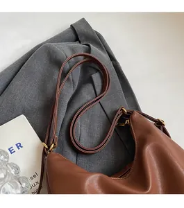 Dettaglio della pelle marrone e degli anelli dorati su una borsa tote da donna