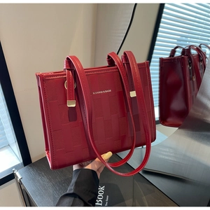Detail of red woven faux leather tote bag with metallic handles and brand logo