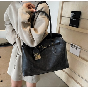 Detailed close-up of retro black matte leather tote bag featuring golden hardware buckle