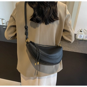 Detail of black lychee grain leather crossbody bag with knot shoulder strap and tassels