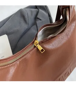 Dettaglio della cerniera in metallo dorato su borsa in pelle marrone con fodera interna