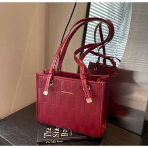 Detail of red tote bag with geometric embossed texture and elegant gold hardware