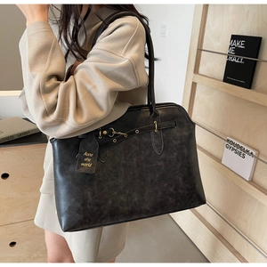 Detail of vintage black tote bag featuring buckle straps and signature leather hangtag