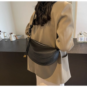 Close-up of black lychee-textured leather crescent bag with knot shoulder strap details