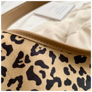 Detailed macro view of leopard print tote bag fabric with premium brown leather piping