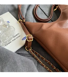 Dettaglio della borsa tote in pelle marrone scuro con catena dorata e tracolla regolabile