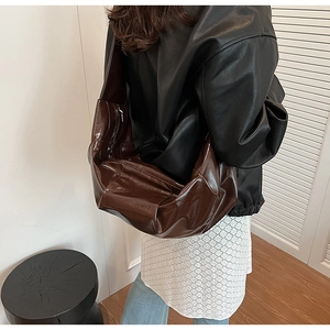 Detail of dark coffee leather hobo bag with pleated texture and wide shoulder strap