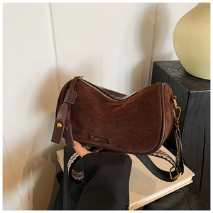 Detail of coffee suede pillow bag with fashion metal tag and printed wide shoulder strap