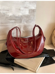 Vintage burgundy leather crescent bag with shoulder straps over a black leather jacket